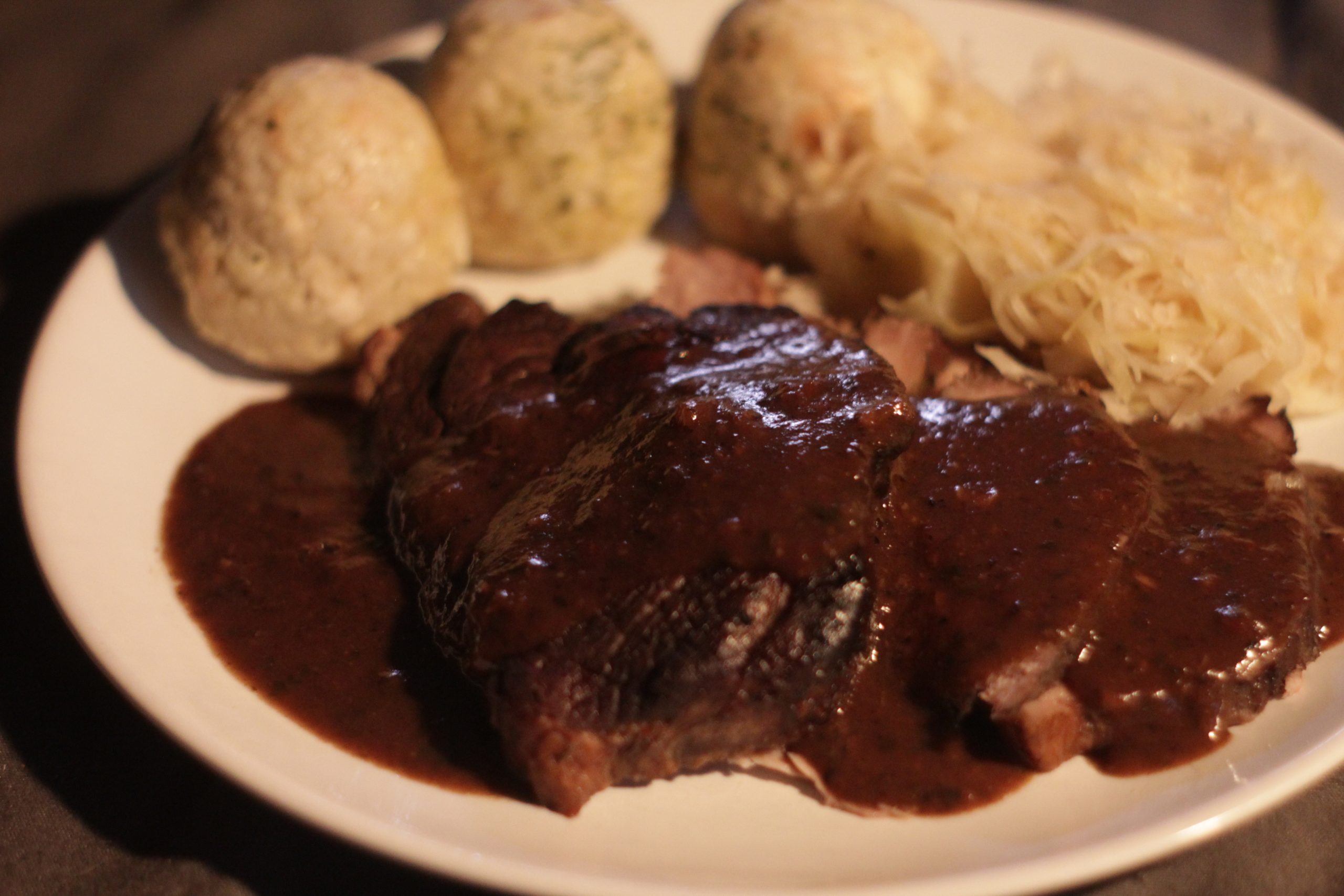 Schweinkamm mit dunkler Soße, dazu Klöße und Sauerkraut